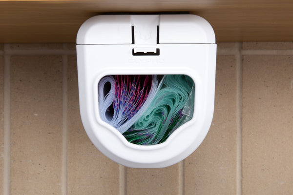 Front view of the dispenser under a cabinet, its window showing the co
