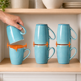 Orange ELYPRO mug stackers holding three pairs of blue mugs on a kitchen cabinet shelf, with a hand lowering one mug into place