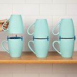 Three pairs of mint mugs joined by blue stackers on a wooden shelf against white kitchen tiles