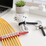 Black, red and white cable ties on a desk holding a coiled extension cord, a phone charger and a row of yellow network cables labelled Phone, Modem, TV, PC and Router