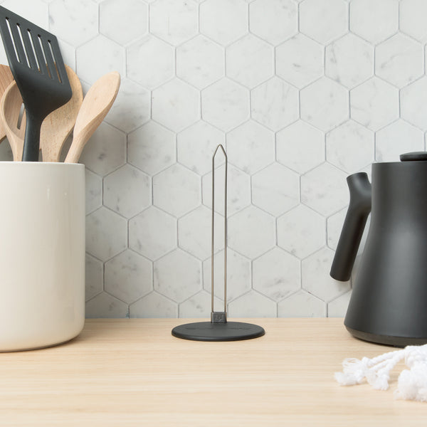 The empty organizer standing on a wooden counter between a utensil crock and a kettle