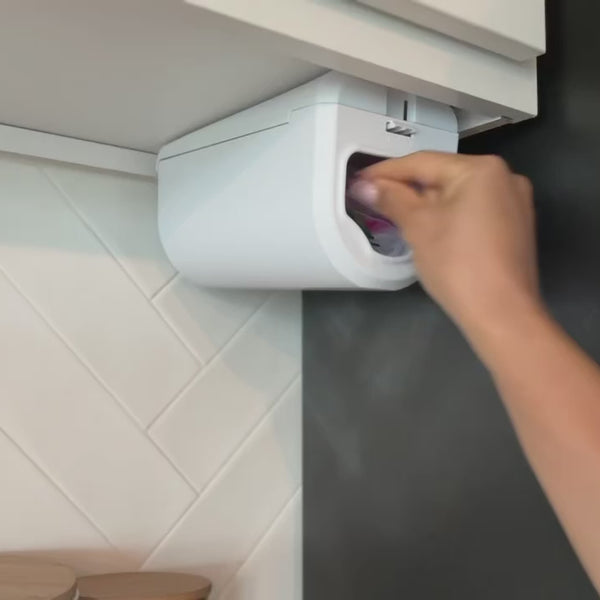 Hand pulling a sandwich bag from the white ELYPRO Ziplock Bag Dispenser mounted under a kitchen cabinet