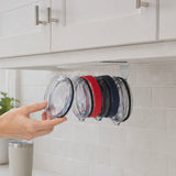 Tumbler lids loaded one at a time onto the ELYPRO under-cabinet organizer fixed beneath a wooden shelf, ending with clear, red and navy lids hanging in a row